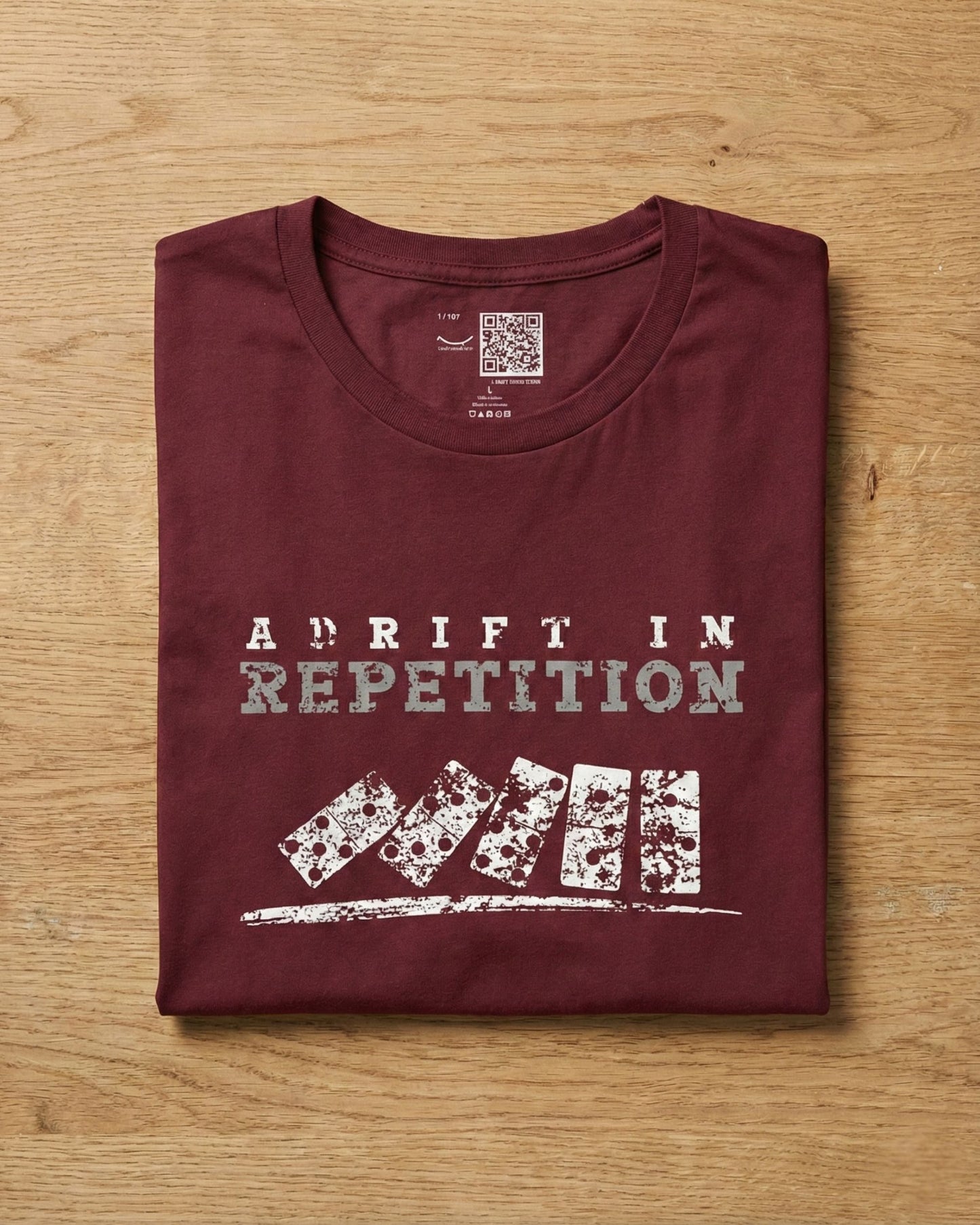 Adrift in Repetition burgundy t-shirt flat lay – falling dominoes with skull faces design – UnseenYou