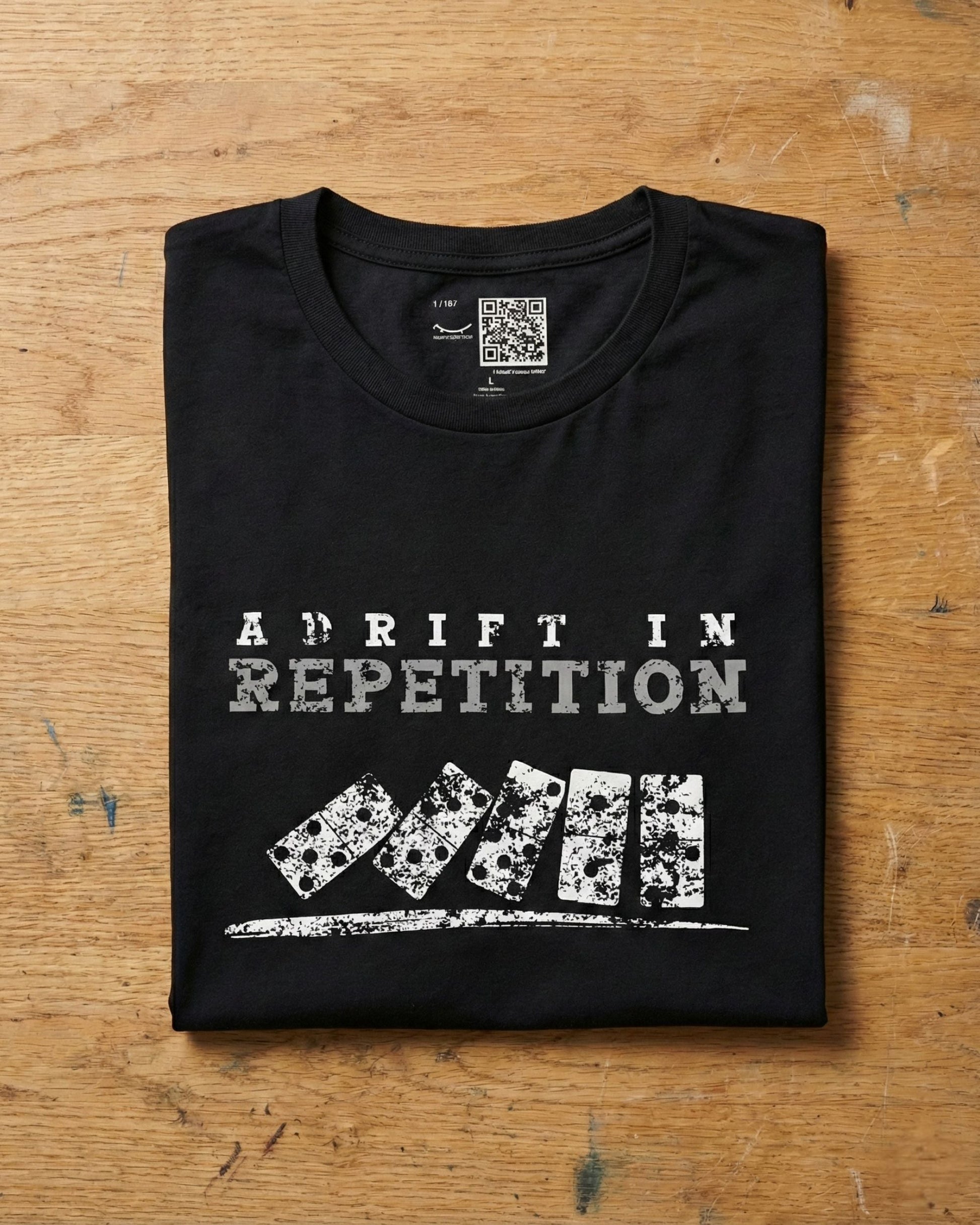 Adrift in Repetition black t-shirt flat lay – falling dominoes with skull faces design – UnseenYou