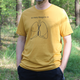 Man wearing a yellow t-shirt with a graphic design and text in a forest setting
